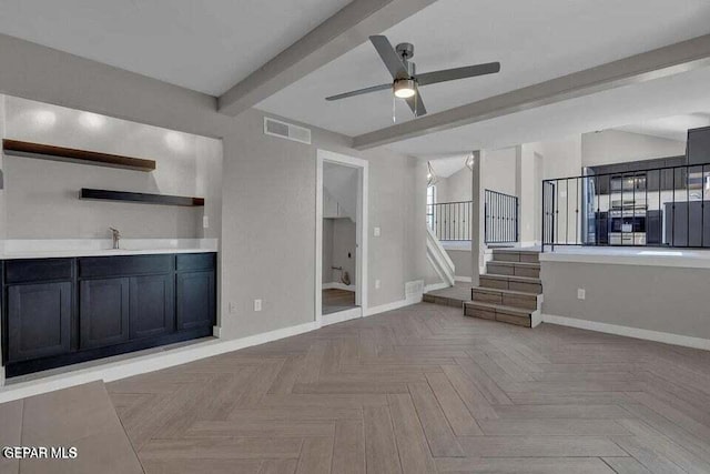 unfurnished living room with beam ceiling, light parquet flooring, ceiling fan, and sink