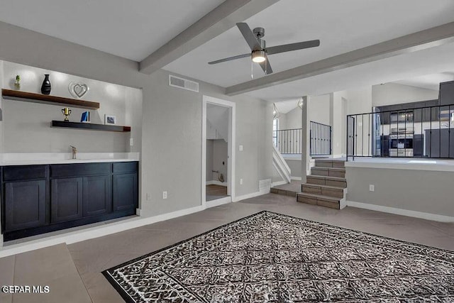 living room with a ceiling fan, baseboards, visible vents, lofted ceiling with beams, and stairs