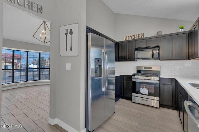 kitchen with backsplash, wood finish floors, light countertops, lofted ceiling, and appliances with stainless steel finishes