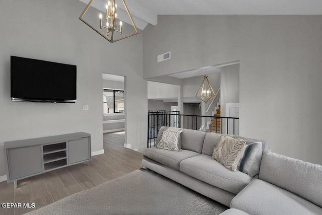 living room featuring visible vents, baseboards, beamed ceiling, wood finished floors, and a notable chandelier