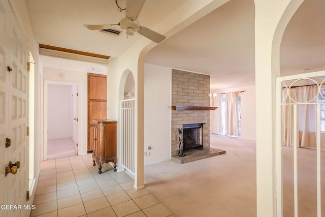 unfurnished living room featuring ceiling fan, light colored carpet, and a brick fireplace