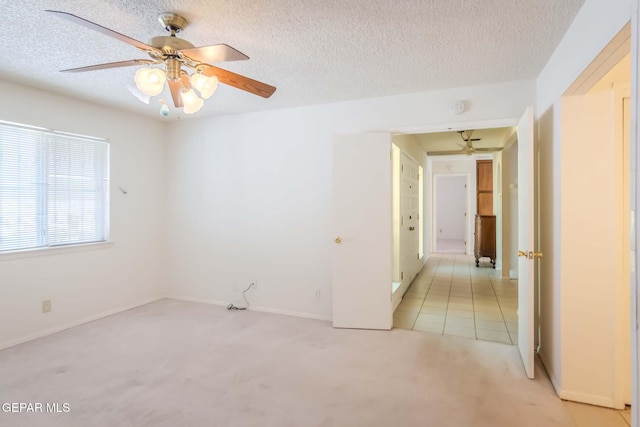 spare room with light carpet, ceiling fan, and a textured ceiling