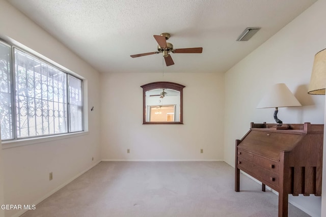 interior space with a textured ceiling, light colored carpet, and ceiling fan