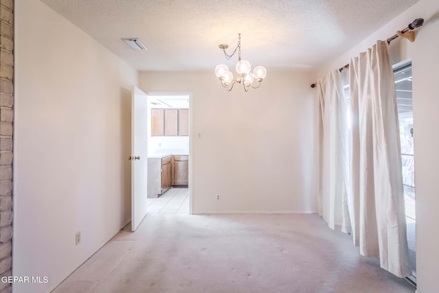 carpeted empty room featuring a chandelier and a textured ceiling