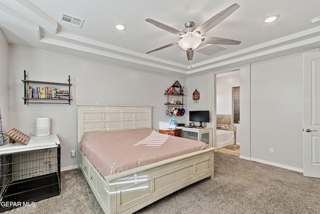 bedroom with light carpet, a tray ceiling, ensuite bath, and ceiling fan