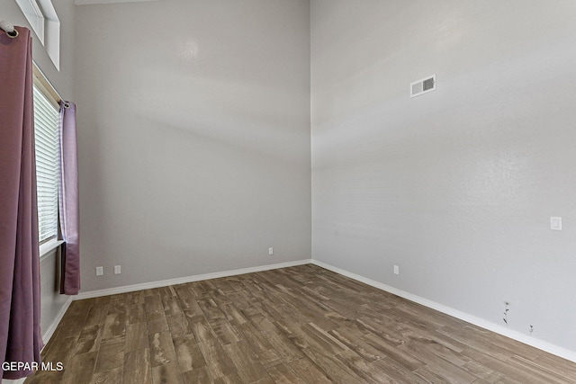 spare room featuring hardwood / wood-style floors and a high ceiling