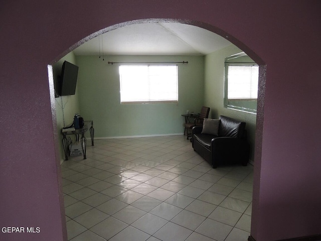 living area featuring light tile patterned floors, vaulted ceiling, and a healthy amount of sunlight