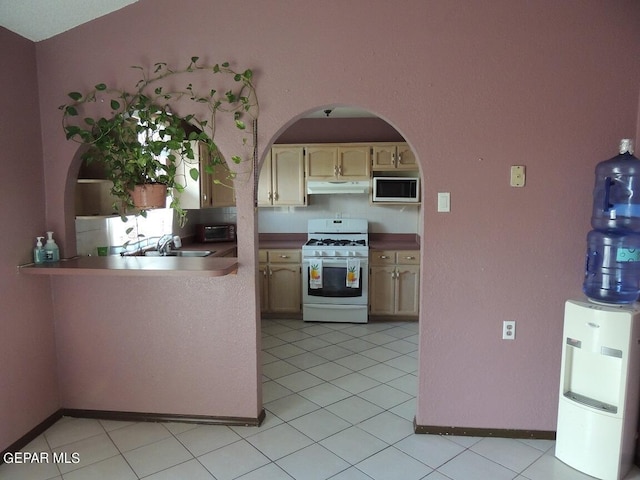 kitchen with light brown cabinets, sink, light tile patterned floors, built in microwave, and white range with gas stovetop