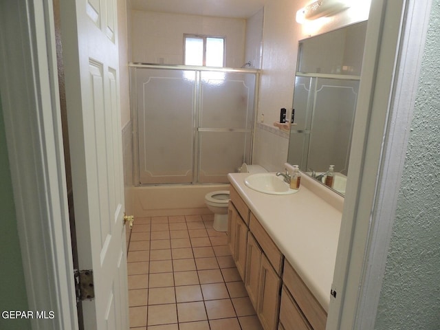 full bathroom featuring tile patterned flooring, vanity, toilet, and bath / shower combo with glass door