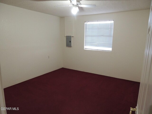 empty room with electric panel, ceiling fan, and a textured ceiling