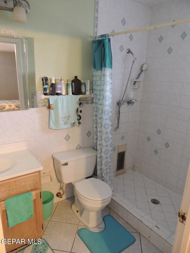 bathroom with vanity, tile patterned flooring, toilet, tile walls, and curtained shower