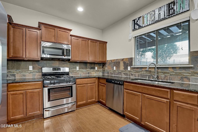 kitchen with dark stone countertops, decorative backsplash, sink, and stainless steel appliances