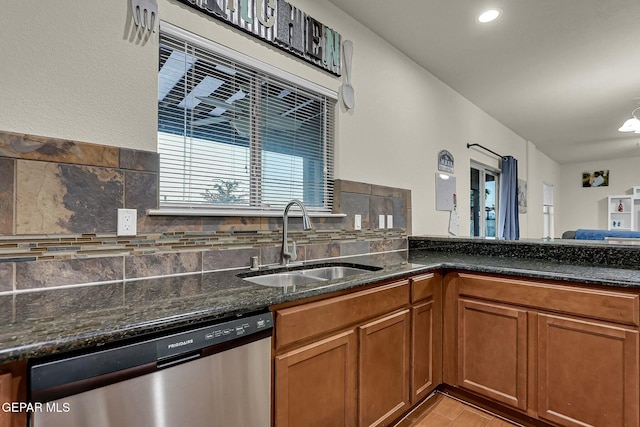 kitchen with dishwasher, sink, dark stone countertops, a chandelier, and decorative backsplash