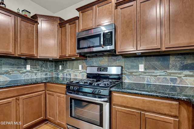 kitchen with decorative backsplash, dark stone countertops, and appliances with stainless steel finishes