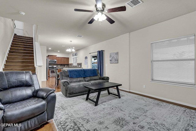 living room featuring light wood-type flooring and ceiling fan with notable chandelier