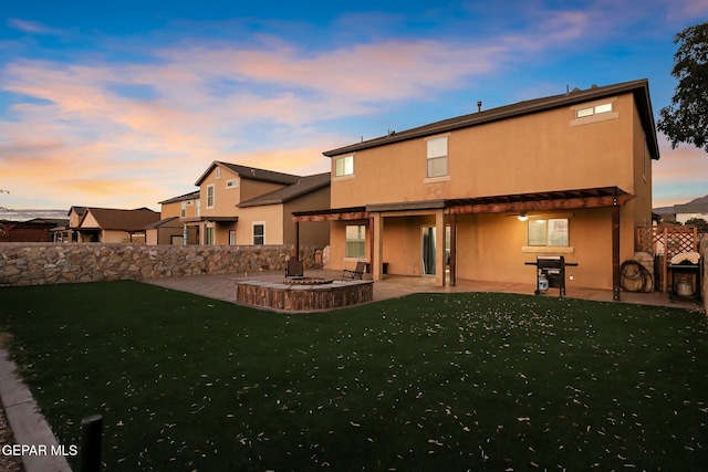 back house at dusk with a yard and a patio