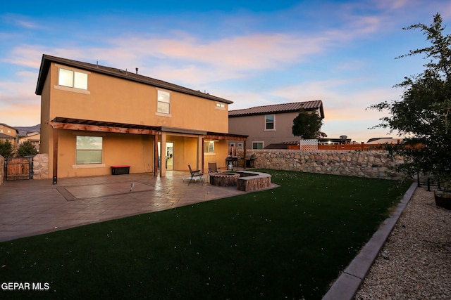 back house at dusk with a yard and a patio