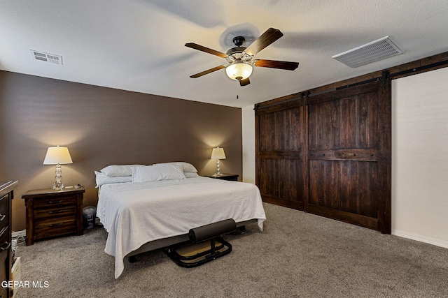 carpeted bedroom featuring a barn door, ceiling fan, and a textured ceiling