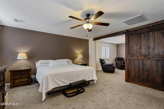 bedroom featuring a barn door, light colored carpet, and ceiling fan