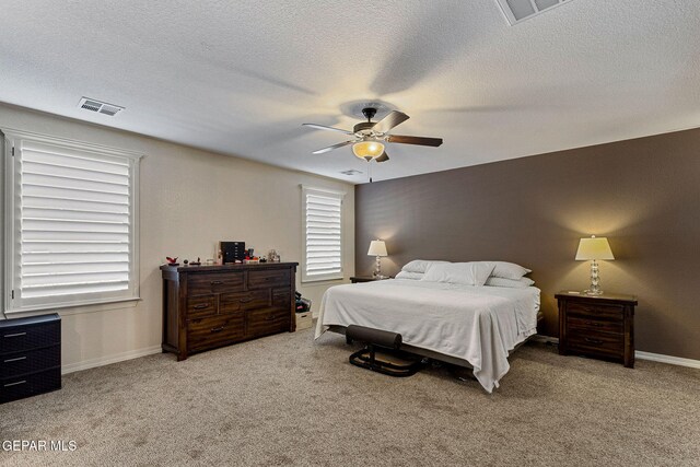 bedroom featuring ceiling fan, light carpet, and a textured ceiling