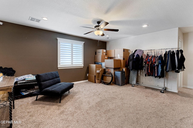 interior space with ceiling fan, light colored carpet, and a textured ceiling