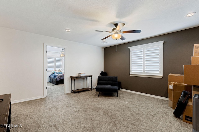 living area featuring light carpet, a textured ceiling, and ceiling fan