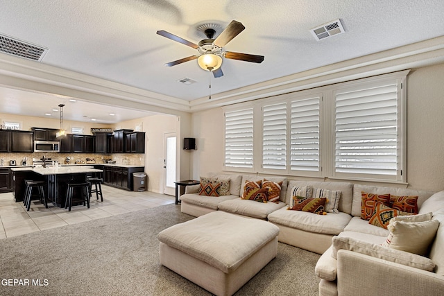 living room with a textured ceiling, ceiling fan, and light tile patterned flooring