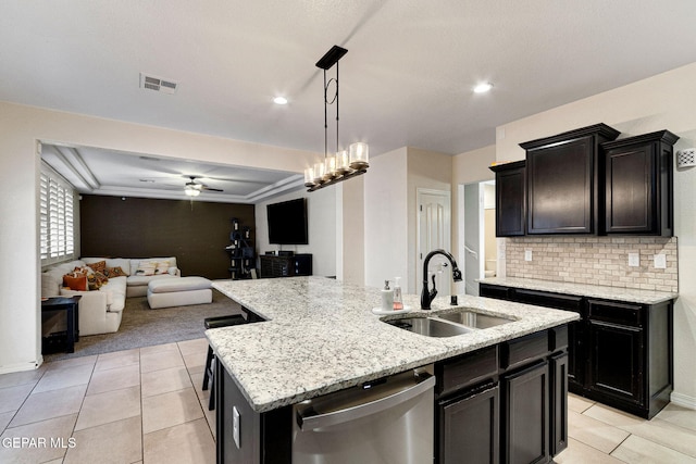 kitchen with sink, hanging light fixtures, stainless steel dishwasher, ceiling fan, and an island with sink