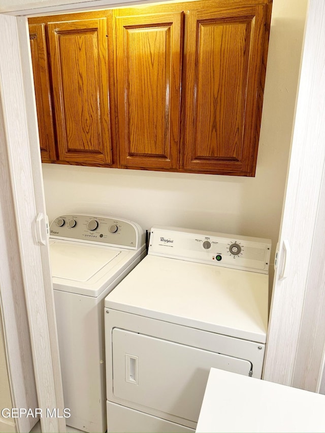 clothes washing area with cabinets and separate washer and dryer