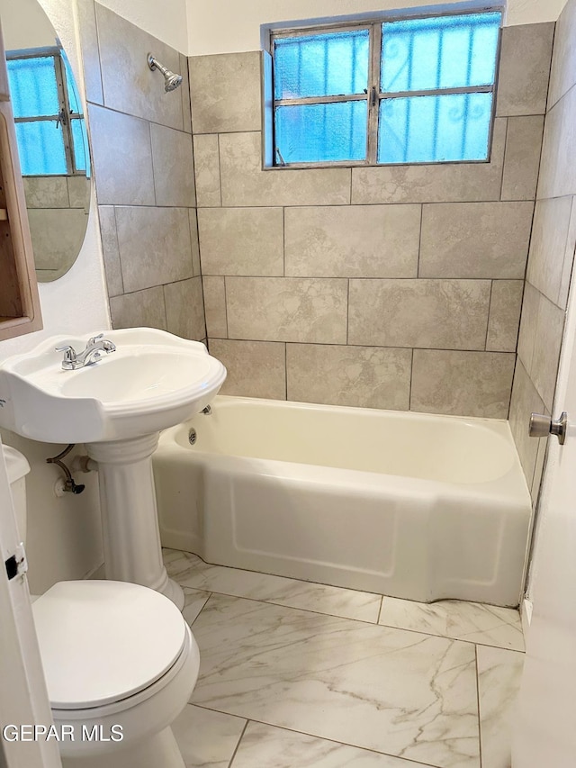 bathroom with toilet and tiled shower / bath