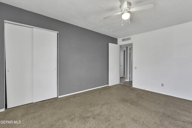 unfurnished bedroom featuring ceiling fan, a closet, dark carpet, and a textured ceiling