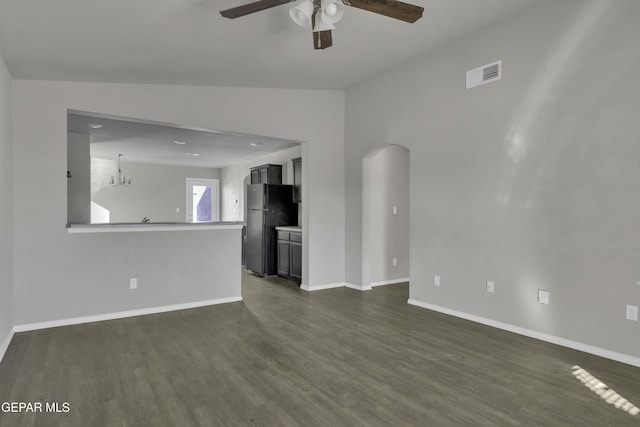 unfurnished living room with dark hardwood / wood-style flooring, ceiling fan with notable chandelier, and vaulted ceiling