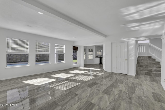 unfurnished living room with beamed ceiling