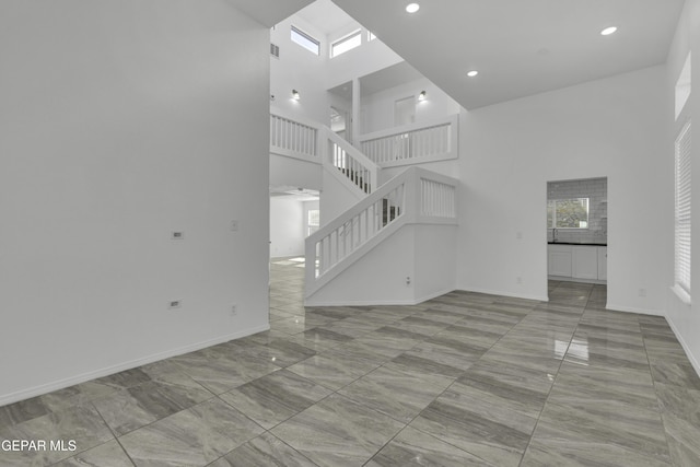 unfurnished living room featuring a towering ceiling