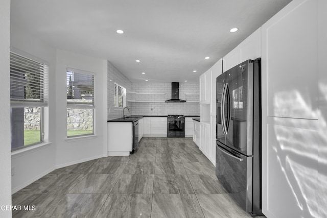 kitchen featuring black appliances, wall chimney exhaust hood, white cabinets, and tasteful backsplash