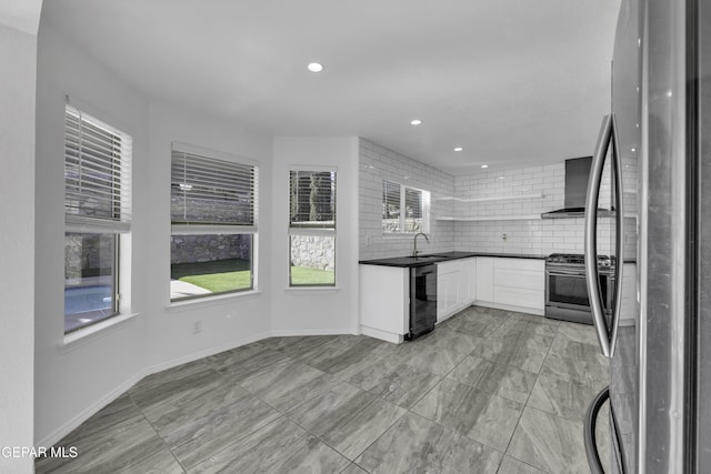 kitchen with a healthy amount of sunlight, white cabinetry, stainless steel appliances, and wall chimney range hood