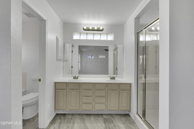 bathroom featuring vanity, toilet, and a shower with shower door