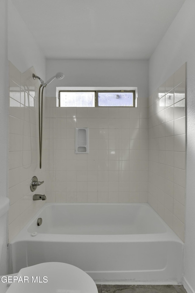 bathroom featuring toilet and tiled shower / bath