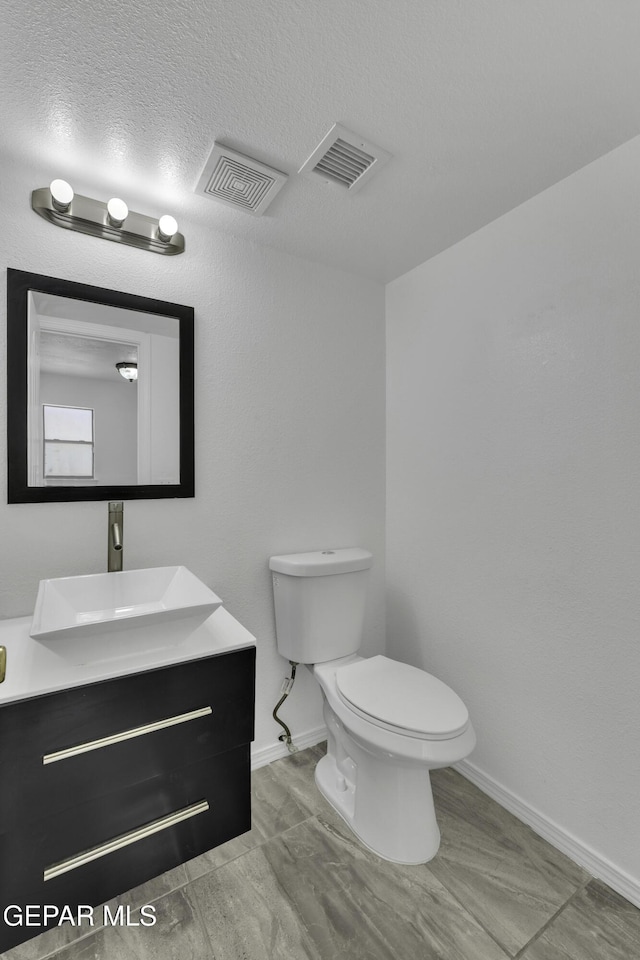 bathroom with vanity, a textured ceiling, and toilet