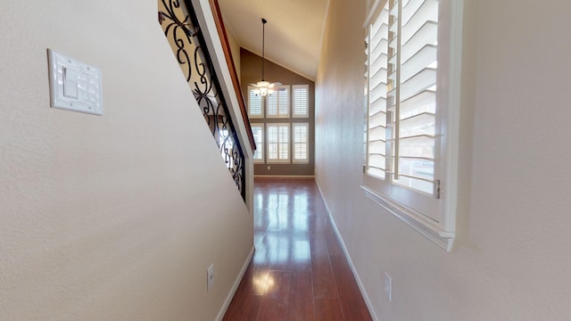 hallway with dark hardwood / wood-style floors, lofted ceiling, and a notable chandelier