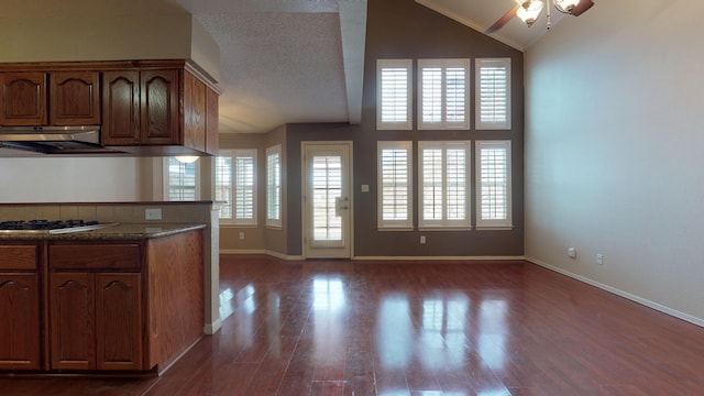 kitchen with dark stone counters, extractor fan, stainless steel gas cooktop, dark wood-type flooring, and ceiling fan