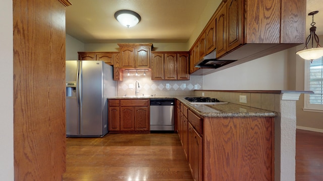 kitchen with stone counters, hanging light fixtures, appliances with stainless steel finishes, tasteful backsplash, and wood-type flooring