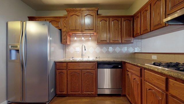 kitchen featuring light stone countertops, sink, backsplash, exhaust hood, and appliances with stainless steel finishes