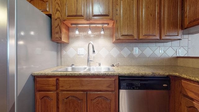 kitchen with backsplash, light stone counters, sink, and appliances with stainless steel finishes