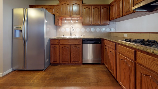 kitchen featuring dark hardwood / wood-style flooring, light stone counters, stainless steel appliances, extractor fan, and sink