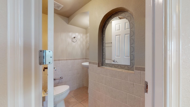 bathroom with tile patterned floors, tile walls, and toilet