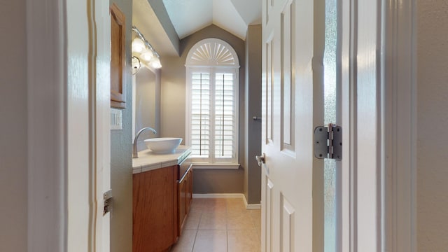 bathroom with tile patterned flooring, vanity, and vaulted ceiling