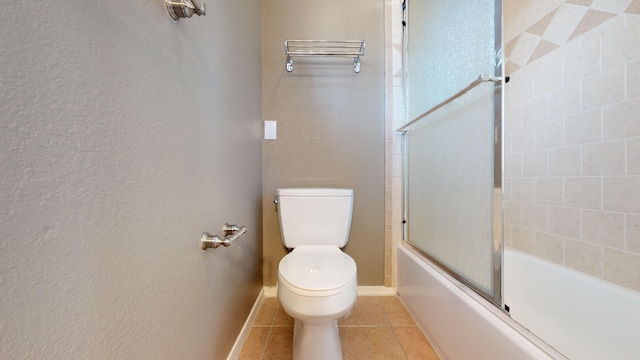 bathroom featuring combined bath / shower with glass door, tile patterned floors, and toilet