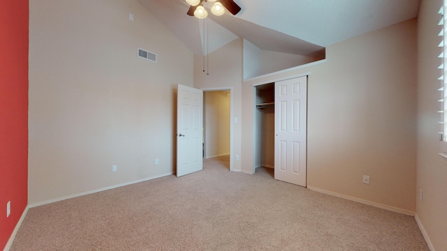 unfurnished bedroom with a closet, light colored carpet, high vaulted ceiling, and ceiling fan