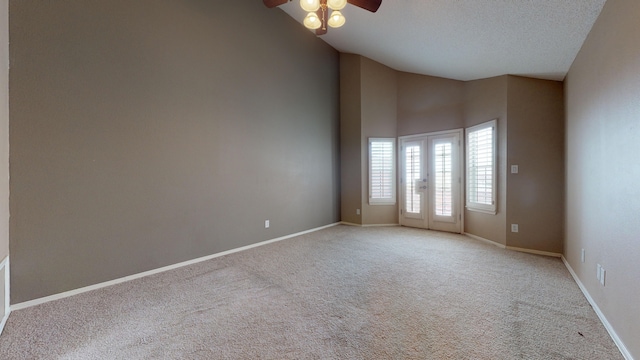 empty room with light carpet, french doors, ceiling fan, a towering ceiling, and a textured ceiling